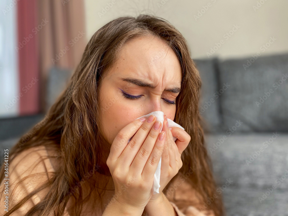 Woman with long hair in a medical mask and a thermometer in her hands. The woman has signs of fever at a high temperature. Pandemic coronavirus. Woman with long hair in a medical mask and a thermometer in her hands. The woman has signs of fever at a high temperature. Pandemic coronavirus.