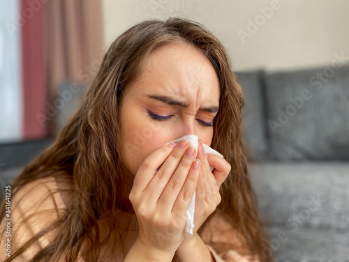 Woman with long hair in a medical mask and a thermometer in her hands. The woman has signs of fever at a high temperature. Pandemic coronavirus.