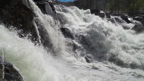 A slow-motion video of the powerful Gaula river at the Likholefossen waterfall. A mass of water falling from the rocks, whirling, foaming and splashing around. Water spray hanging in the air. photo