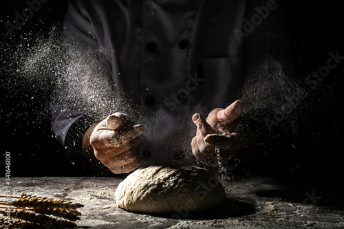 Photo of flour and men hands with flour splash. Cooking bread. Kneading the Dough. Isolated on dark background. space for text