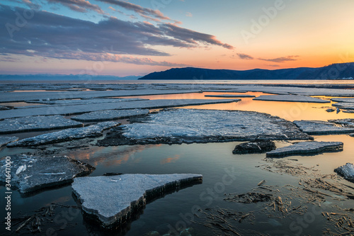 Ice drift on lake Baikal near the source of the Angara river at sunset