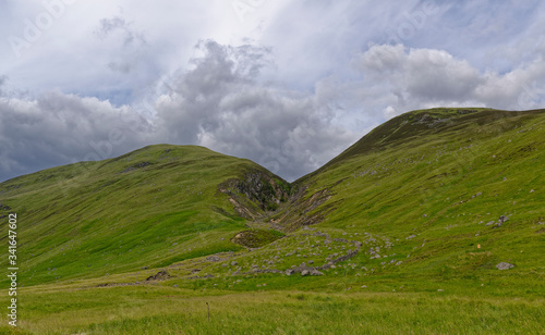 A Water eroded Fault line on the Valley sides of Glen Doll splitting Two Hills, with an old damaged and ruined stone Sheep Pen in the foreground photo