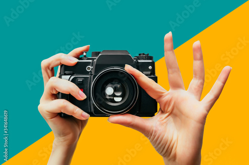 Vintage Camera in female hand. A photo. Photographer. Manual focus. Colored background.