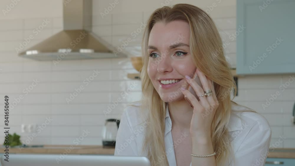 Young pretty woman talking cell phone. Work online at home. Use laptop. Young pretty woman talking cell phone. Work online at home. Use laptop.