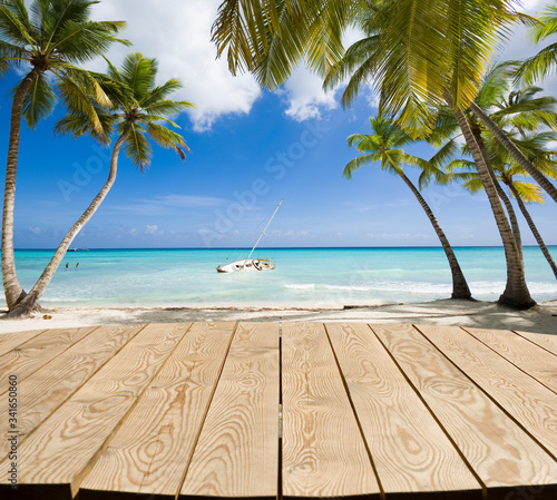 Empty wooden tabletop for Your product advertisement. Tropical beach in Caribbean sea at Saona island in the background  Dominican Republic