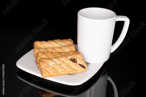 Lot of whole square puff cookie with raisins with coffee isolated on black glass