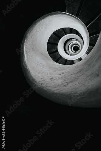 Black and white image of spiral stairs looking down from the top, creating an interesting perspective. 