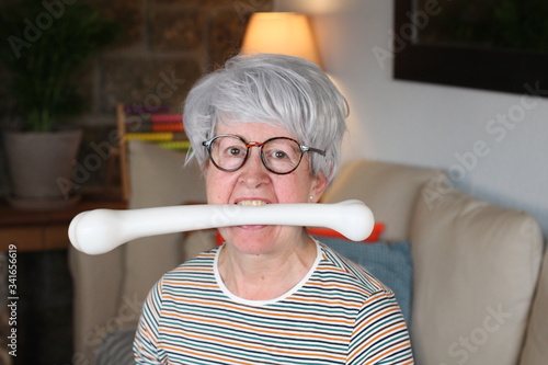 Hilarious senior woman holding bone with mouth photo