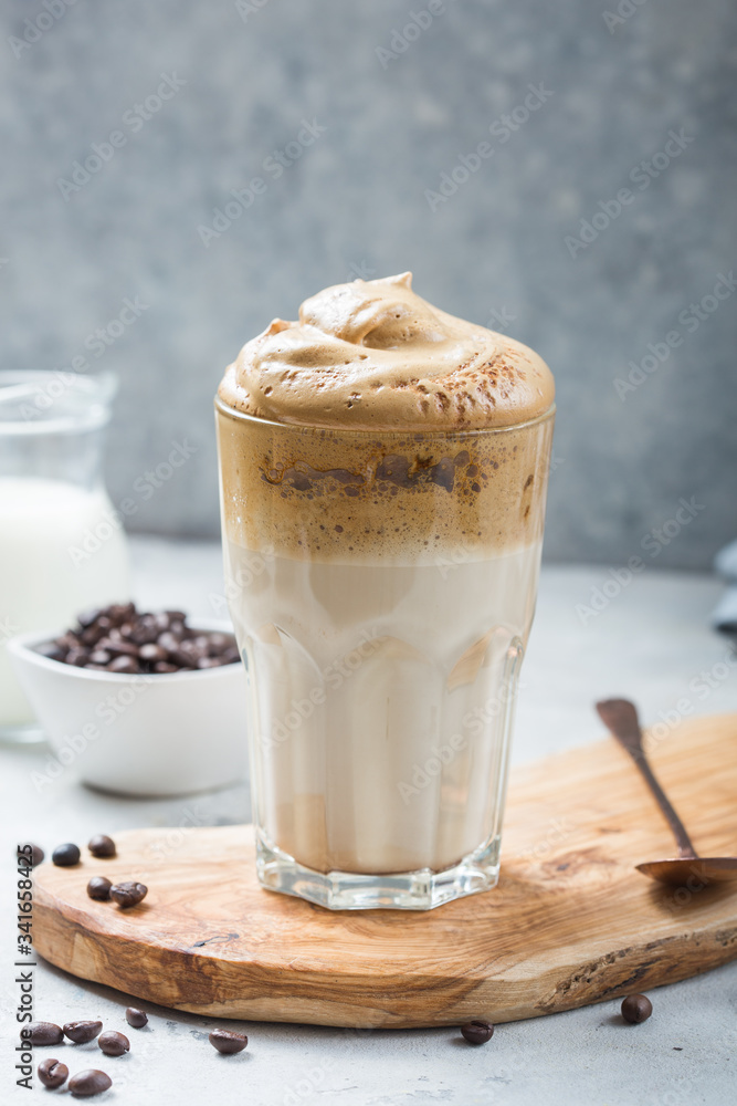 Dalgona frothy coffee in glass on grey. Trend korean drink latte with foam of instant coffee. Close up. Dalgona frothy coffee in glass on grey. Trend korean drink latte with foam of instant coffee. Close up.