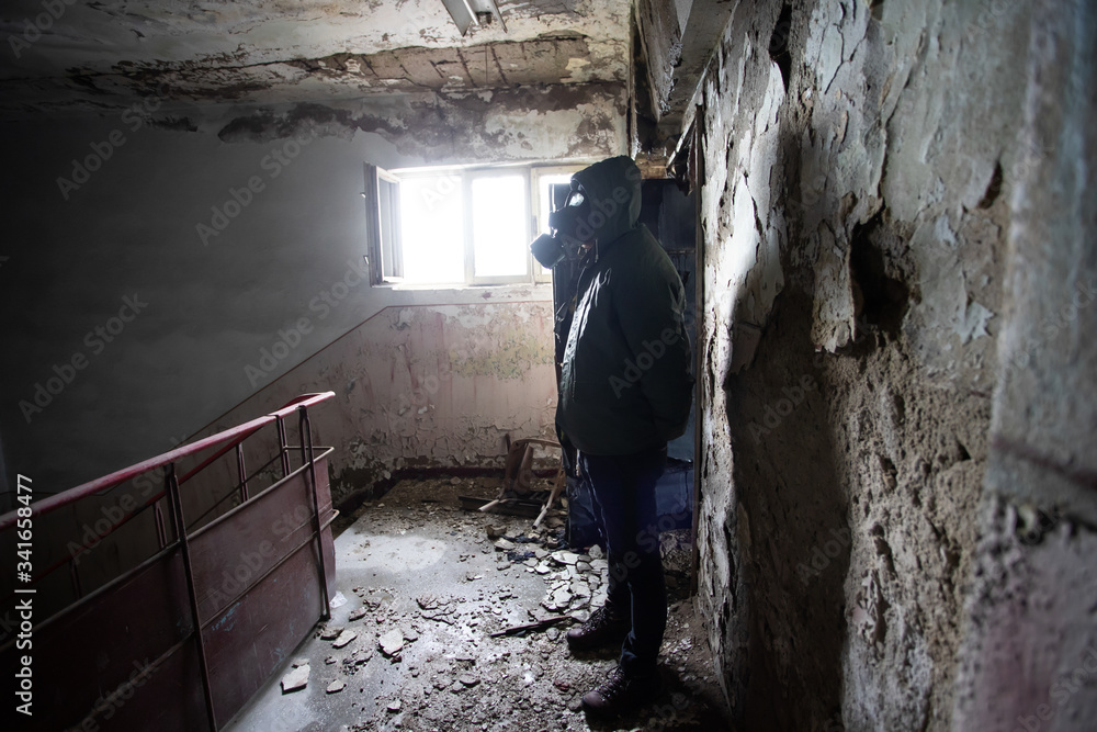 Dramatic portrait of a man wearing a gas mask in a ruined building.