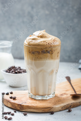 Dalgona frothy coffee in glass on grey. Trend korean drink latte with foam of instant coffee. Close up.
