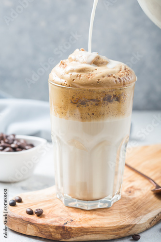 Dalgona frothy coffee in glass on grey. Trend korean drink latte with foam of instant coffee. Close up. © Maria