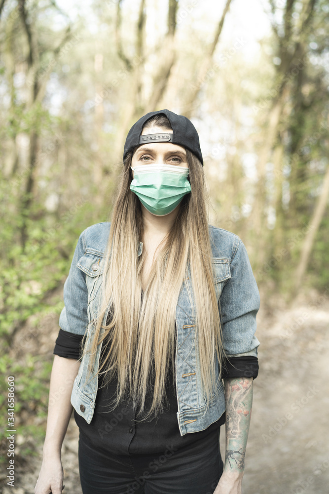 Casual Woman Face Portrait Wearing Surgical Mask in Forest or Park. Coronavirus Epidemic New Normal Life Casual Woman Face Portrait Wearing Surgical Mask in Forest or Park. Coronavirus Epidemic New Normal Life