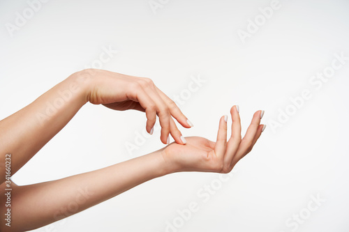 Indoor shot of young attractive female's raised hand touching gently with fingers another hand white being isolated against white background