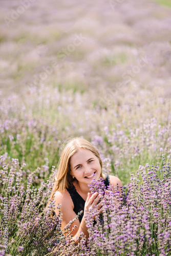 Beautiful girl in dress in purple lavender field. Beautiful woman walk on the lavender field. Girl collect lavender. Enjoy the floral glade, summer nature. Natural cosmetics and eco makeup concept.