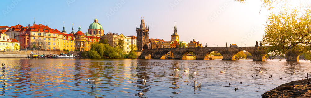 Fototapeta premium View on Charles bridge and Swans on Vltava river in Prague at sunset, Czech Republic