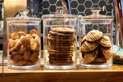 Obraz na płótnie Variety of cookies in three glass jars on a counter at coffee shop