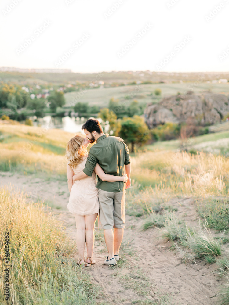 Young couple in love outdoor. Stunning sensual outdoor portrait of young stylish fashion couple posing in summer in field. Film photography. Pretty family hugging and flirting in an park Young couple in love outdoor. Stunning sensual outdoor portrait of young stylish fashion couple posing in summer in field. Film photography. Pretty family hugging and flirting in an park