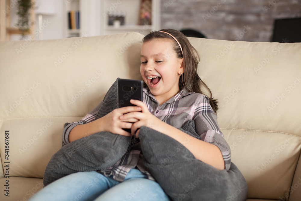 Happy little girl sitting on the couch in living room Happy little girl sitting on the couch in living room