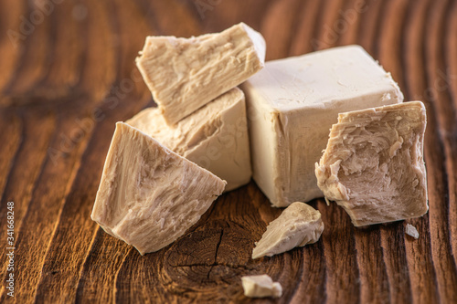 Slika na platnu cube of fresh yeast whole and crumbled on a old vintage wood board background