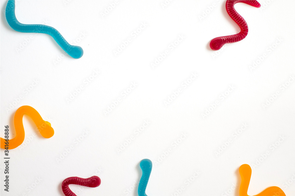 jelly fruit candies of different colors in the form of worms on a white paper background. Imitation of crawling candy on paper jelly fruit candies of different colors in the form of worms on a white paper background. Imitation of crawling candy on paper