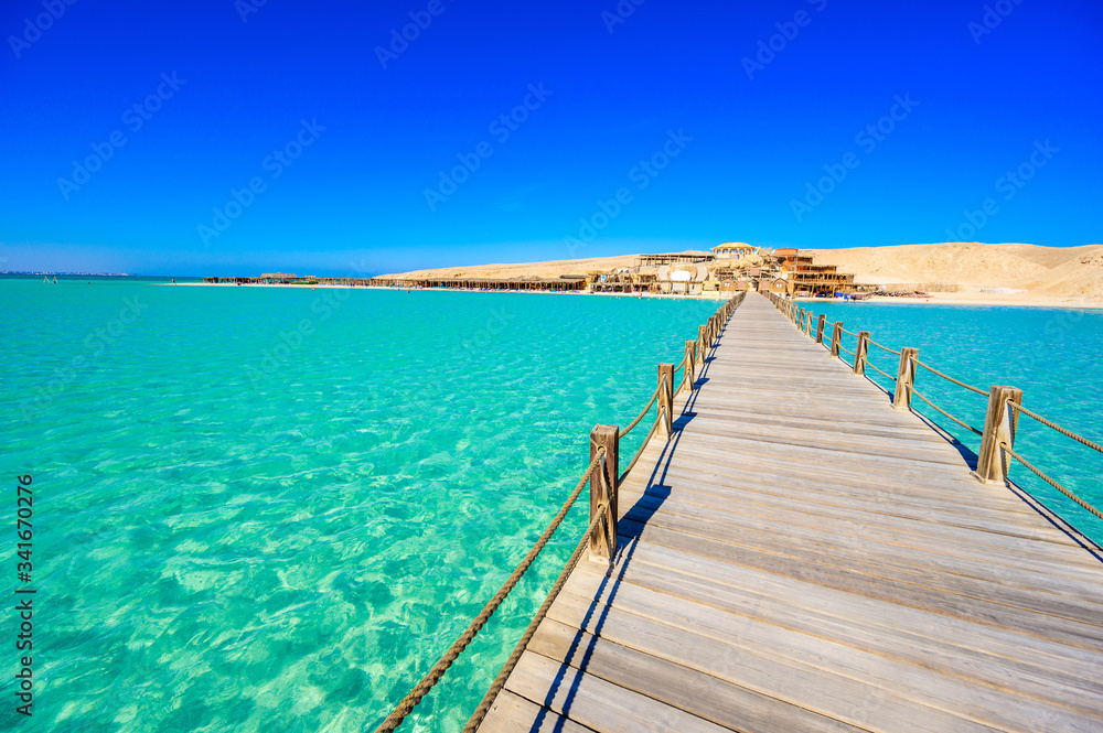 Wooden Pier at Orange Bay Beach with crystal clear azure water and white beach - paradise coastline of Giftun island, Mahmya, Hurghada, Red Sea, Egypt.