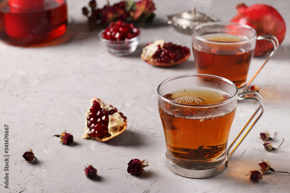 Pomegranate tea in two transparent cups on a gray concrete background, warming wellness drink Pomegranate tea in two transparent cups on a gray concrete background, warming wellness drink