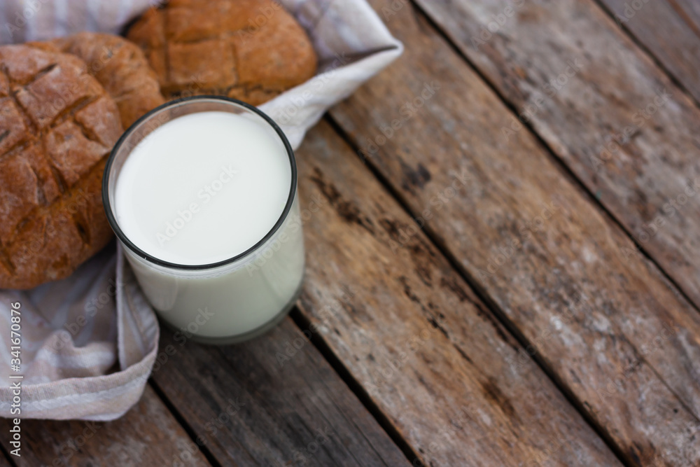 Glass of fresh milk and round brown rye flatbread on a rustic wooden table. Vegetable milk, vegan milk, Kefir, or Turkish Ayran drink for helthy eating. Space for text. Top view Glass of fresh milk and round brown rye flatbread on a rustic wooden table. Vegetable milk, vegan milk, Kefir, or Turkish Ayran drink for helthy eating. Space for text. Top view
