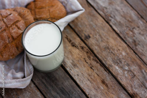Glass of fresh milk and round brown rye flatbread on a rustic wooden table. Vegetable milk  vegan milk  Kefir  or Turkish Ayran drink for helthy eating. Space for text. Top view