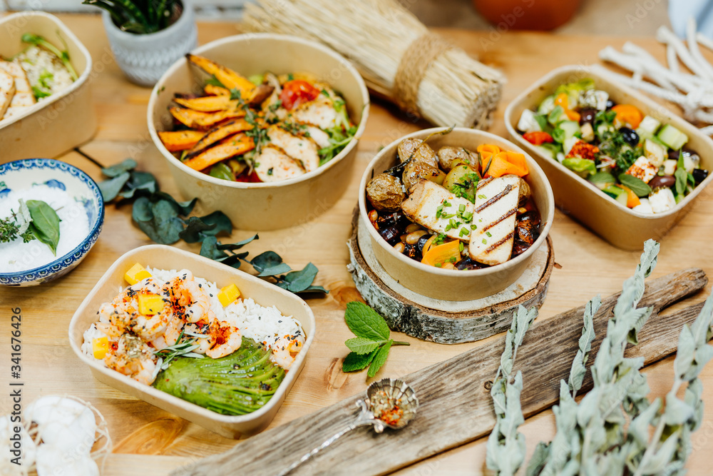 Various healthy and vitamin-rich dishes and food in an ecobox delivered by a delivery service, ordered online, decorated with bundles of straw, mussels and cacti, in a Mediterranean style Various healthy and vitamin-rich dishes and food in an ecobox delivered by a delivery service, ordered online, decorated with bundles of straw, mussels and cacti, in a Mediterranean style