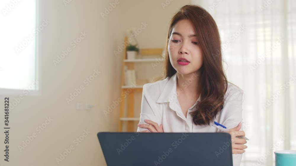 Asian businesswoman using laptop talk to colleagues about plan in video call while smart working from home at living room. Self-isolation, social distancing, quarantine for coronavirus prevention. Asian businesswoman using laptop talk to colleagues about plan in video call while smart working from home at living room. Self-isolation, social distancing, quarantine for coronavirus prevention.