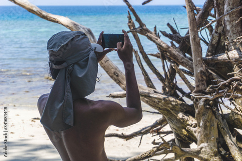 Photography man taking photo of a huge dead tree on the beach in havelock andaman india