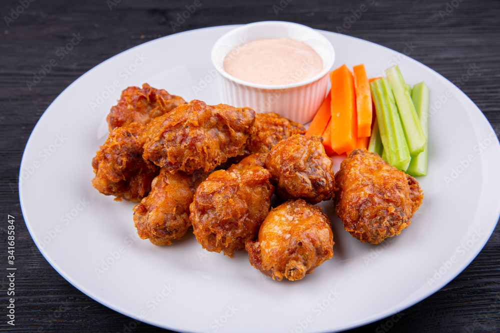 Fried legs and wings with breading, served with sauce and vegetables Fried legs and wings with breading, served with sauce and vegetables
