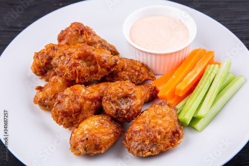 Fried legs and wings with breading, served with sauce and vegetables