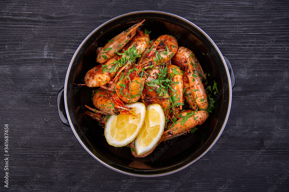 Fototapeta premium Fried shrimp on oil, served with greens and lemon