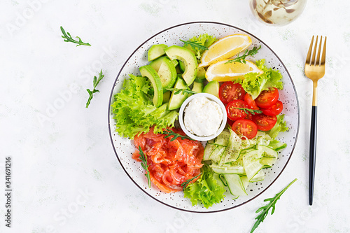 Salad of salted fish salmon, avocado, cherry tomatoes, cucumber, lettuce and cream cheese. Fish menu. Dietary menu. Seafood - salmon. Top view, overhead, flat lay