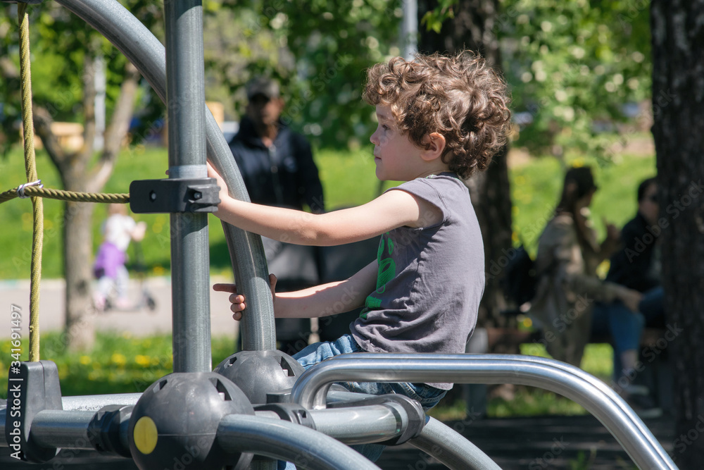 Six-year-old boy plays on the playground in the city park. Moscow, Russia.