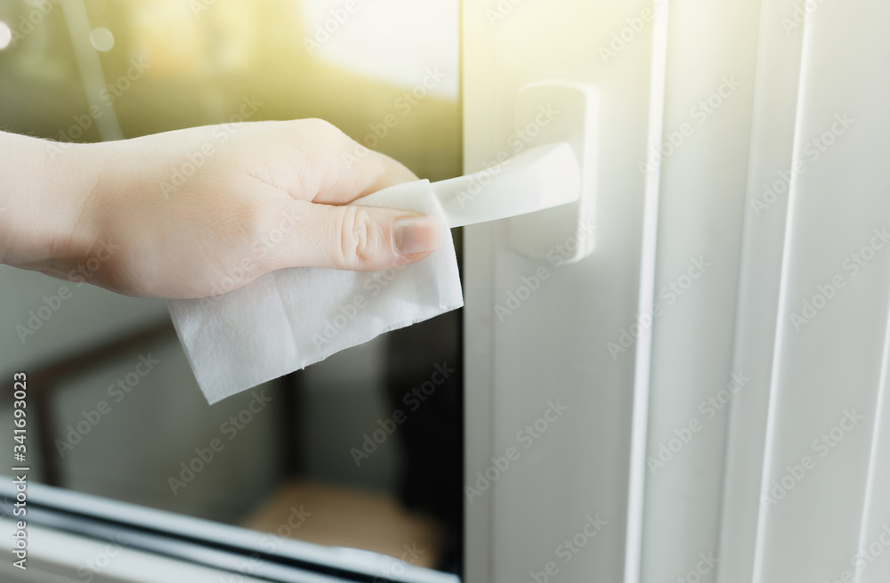 closeup female hands with a wet towel wipe the handle of a white door from viruses closeup female hands with a wet towel wipe the handle of a white door from viruses