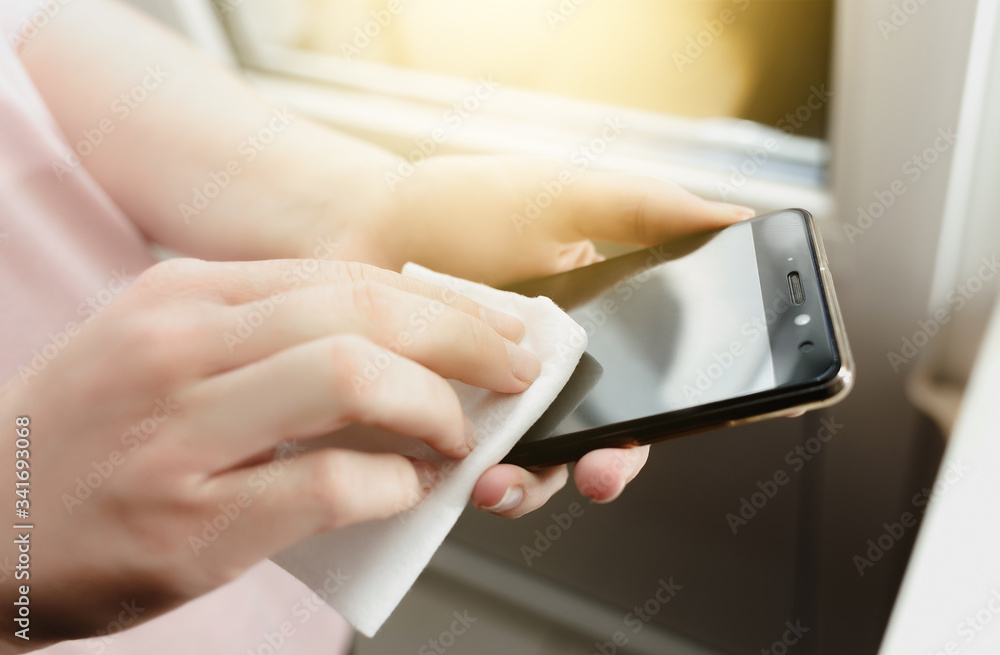 close-up female hands wipe smartphone with wet wipe from viruses