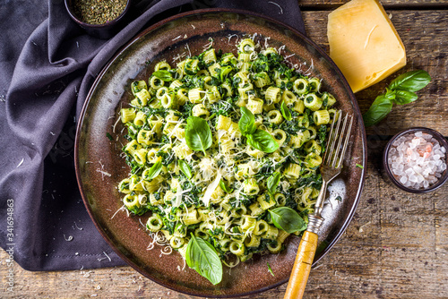 Ditaloni rigati spring recipe, Green ditalini pasta with spinach, green pesto sauce and cheese, rustic wooden background photo