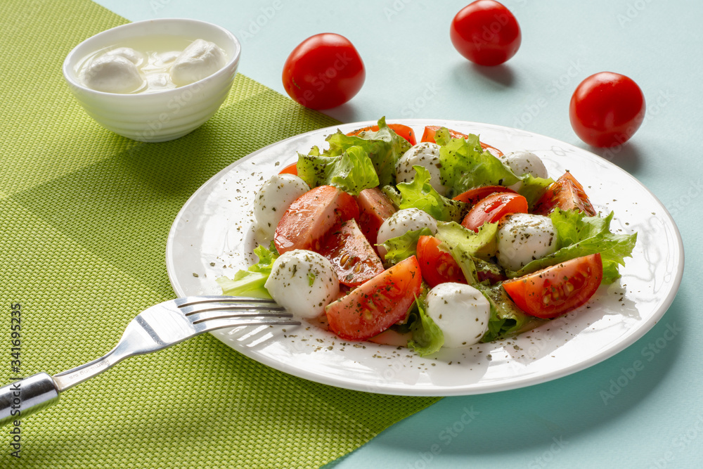 Salad with cherry tomatoes, lettuce, mozzarella and lemon-oil dressing