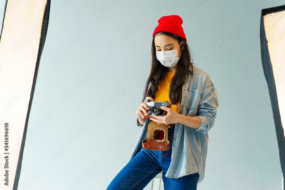 Medium shot woman with camera and mask in photography studio. Medium shot woman with camera and mask in photography studio.