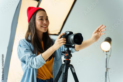 Smiley photographer taking shots. Asian woman in photography studio.