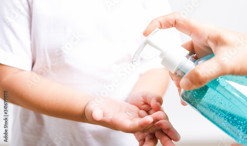Mother applying pump dispenser alcohol gel cleaning washing hands little child