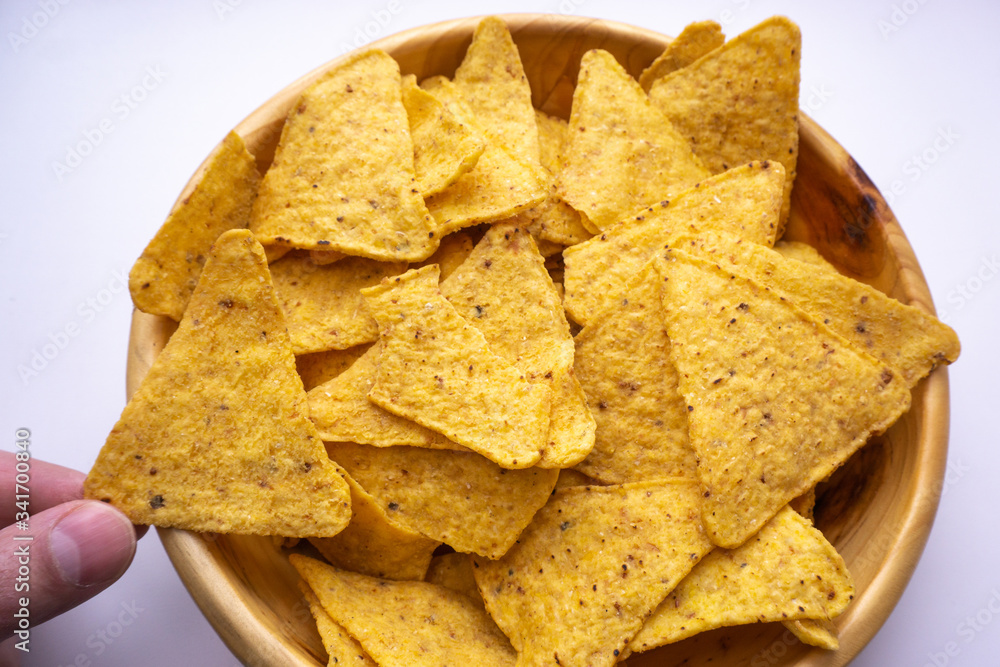 eating tasty corn chips hand takes nacho from a plate close up eating tasty corn chips hand takes nacho from a plate close up