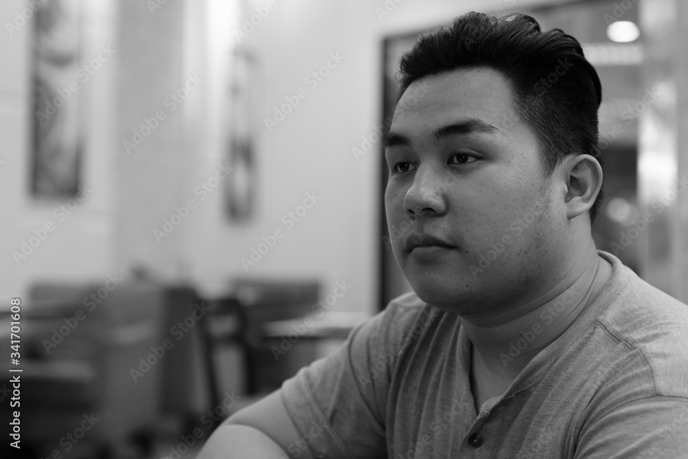 Face of young overweight Asian man thinking at the coffee shop Face of young overweight Asian man thinking at the coffee shop
