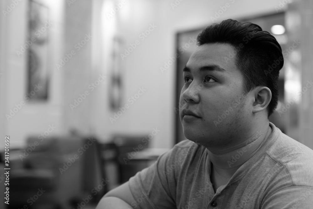 Face of young overweight Asian man thinking at the coffee shop Face of young overweight Asian man thinking at the coffee shop