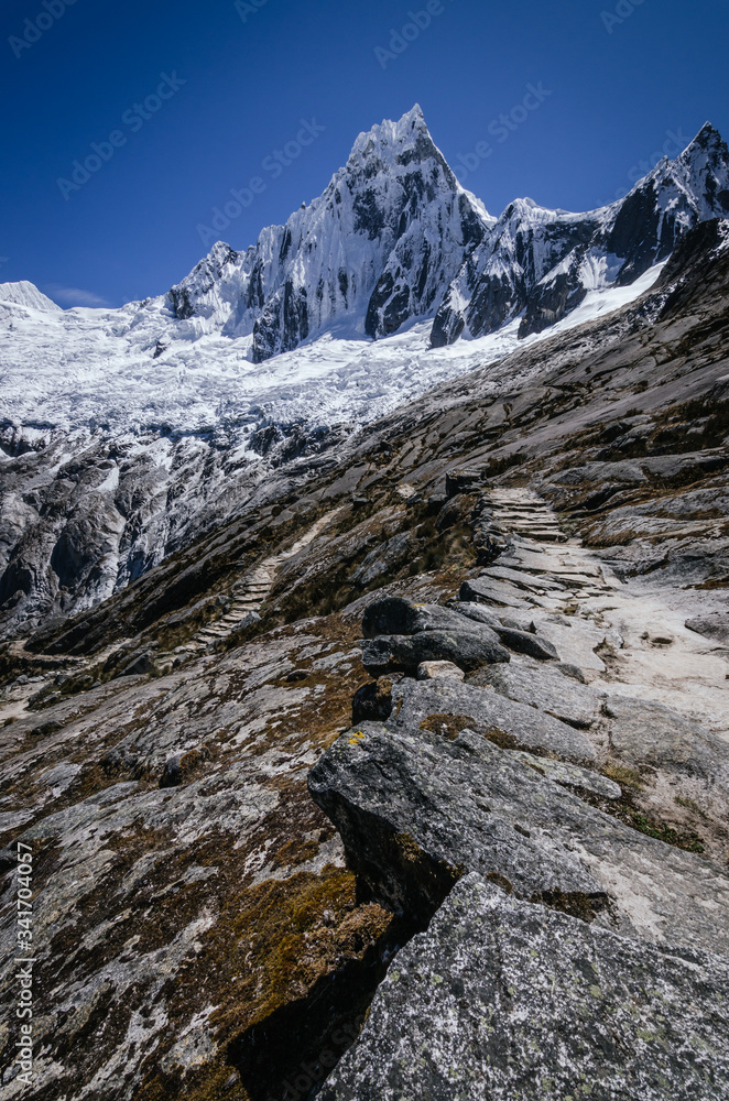rocky road that leads to the high snowy mountain of Taulliraju, in the trekking of the quebrada santa cruz in peru