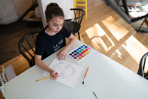 Teenage girl drawing a self portrait at the kitchen table photo