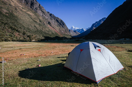 gray camping tent with high snowy mountains in the background, on the trekking of the quebrada santa cruz in peru